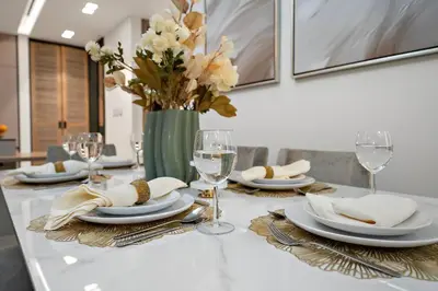 a table with plates and glasses and a vase with flowers at FIRST CLASS 3BR Lively Sanctuary in Dubai