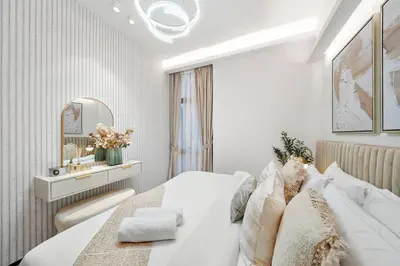 a white bedroom with a bed and a mirror at FIRST CLASS 3BR Lively Sanctuary in Dubai