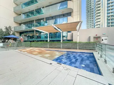 a building with a swimming pool in front of a building at 1BR Dubai, Merano Canal View Retreat Near Metro Dining Shopping Mall in Dubai