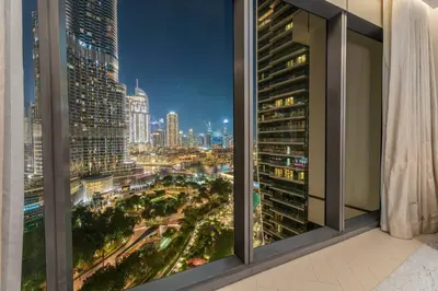 a view of a city at night from a window at Family 3BR Flat Free Parking, Gym, Pool & Burj Views in Dubai