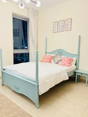 a bedroom with a blue bed with pink pillows at 1 BHK Apartment in Dubai in front of Burj Khalifa in Dubai