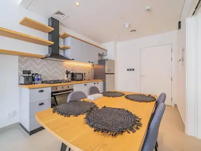 a kitchen with a wooden table with mats on it at Dubai Hills estate - 1Bedroom Apt in Dubai