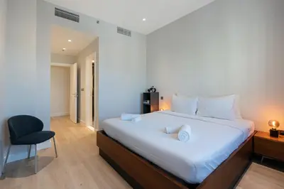 a bedroom with a large white bed and a chair at Al Andalus Tower F, Cadiz JGE - 3BR Apartment - Allsopp & Allsopp in Dubai