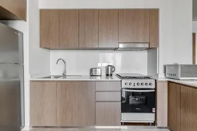 a kitchen with wooden cabinets and a stove top oven at Knokey Luxury 1BR Apartments - 5 min walk to Burj Khalifa & Dubai Mall & Dubai Fountain in Dubai