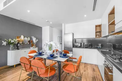 a kitchen with a table with orange chairs in it at EDEN'S Homes & Villas - VIDA Dubai Marina Residences in Dubai