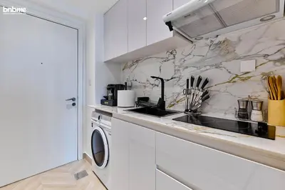 a white kitchen with a sink and a washing machine at bnbme - Stylish JLT Studio Near Metro Rooftop Pool Gym Balcony Marina Access in Dubai