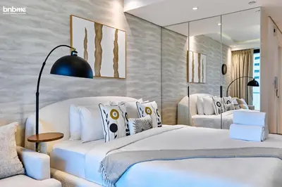 a bedroom with two beds and a mirror at bnbme - Stylish JLT Studio Near Metro Rooftop Pool Gym Balcony Marina Access in Dubai
