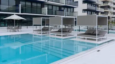 a swimming pool with two lounge chairs and a building at Sleek 1br In Jvc Free Parking Pool & Balcony in Dubai