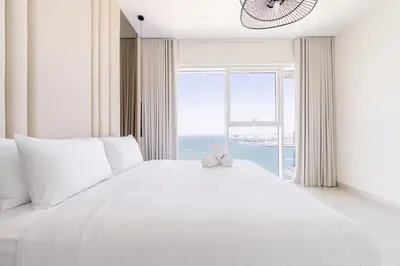 a white bed with a teddy bear sitting on it at Luxury Coastal Escape - Bright 3BR Apt - La Vie JBR in Dubai