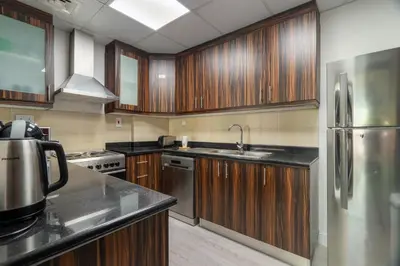 a kitchen with wooden cabinets and a stainless steel refrigerator at GuestReady - Charming retreat in Dubai Marina in Dubai