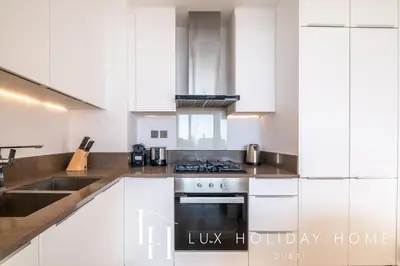 a kitchen with white cabinets and a sink and a stove at LUX The Marina Gate Sea View Suite 2 in Dubai