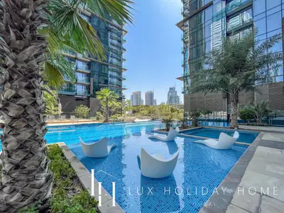 a swimming pool with white chairs and a palm tree at LUX The Marina Gate Sea View Suite 2 in Dubai