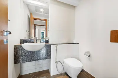 a white bathroom with a sink and a toilet at Spacious 1-Bedroom Apartment In Bay Square in Dubai
