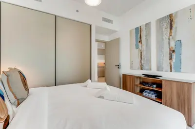 a bedroom with a large white bed and a cabinet at Coastal Chic 1 Bedroom Apartment w private beach in Dubai