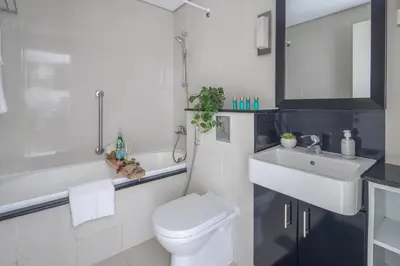 a white bathroom with a toilet and a sink at Frank Porter - Damac Cour Jardin in Dubai