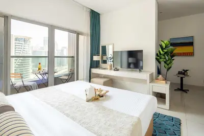 a bedroom with a large white bed and a television at Frank Porter - Damac Cour Jardin in Dubai