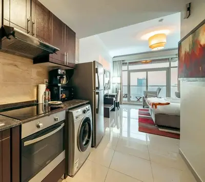 a kitchen with a washer and dryer and a bedroom at Comfortable Fully Furnished Studio l Ideal Living Space in Dubai