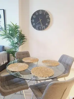 a glass table with chairs and a clock on a wall at Luxury 42-Floor 1BR flat in Harbour Views in Dubai