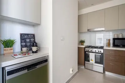 a kitchen with white cabinets and a stove top oven at Frank Porter - Forte Tower 1 in Dubai