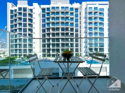 a table and chairs on a balcony with a large building at Urban Charm Studio with Balcony in Riviera in Dubai