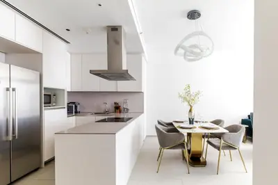 a kitchen with white cabinets and a table with chairs at Panoramic Sea & Palm Views 2BR Address Beach Resort JBR in Dubai