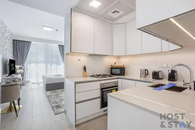 a kitchen with white cabinets and a stove top oven at Charming Studio in Luma 22, Jumeirah Village Circle in Dubai