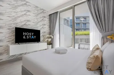 a bedroom with a bed and a tv on a wall at Charming Studio in Luma 22, Jumeirah Village Circle in Dubai