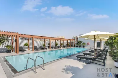a swimming pool with chairs and an umbrella at Charming Studio in Luma 22, Jumeirah Village Circle in Dubai