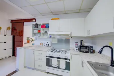a white kitchen with a stove and a sink at Ramadan Staycation offers Miracle Home Haven in Dubai