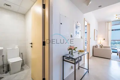 a room with a toilet and a table with flowers on it at Lovely 1BR in Binghatti Avenue Al Jaddaf by Deluxe Holiday Homes in Dubai