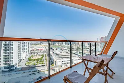 a balcony with a wooden table and a chair at Lovely 1BR in Binghatti Avenue Al Jaddaf by Deluxe Holiday Homes in Dubai
