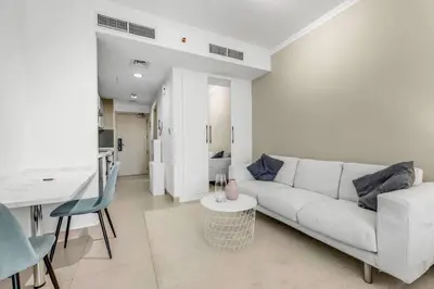 a white living room with a white couch and a table at Waves - Charming Studio with Lake Views Close to Metro in Dubai