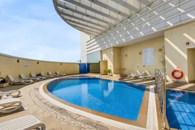 a swimming pool in a building with chairs around it at Waves - Charming Studio with Lake Views Close to Metro in Dubai