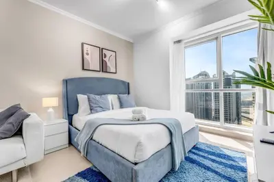 a bedroom with a blue bed and a window at Waves - Charming Studio with Lake Views Close to Metro in Dubai