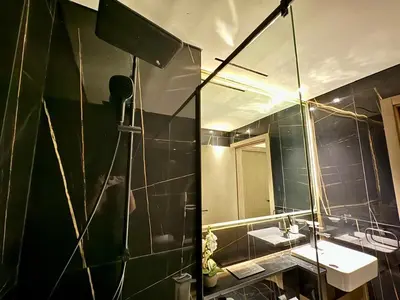 a man taking a picture of a bathroom with a mirror at Luxe 2br With Fast Wi-fi Parking, Gym And Pool! in Dubai