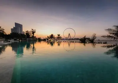 a large pool of water with a ferris wheel in the background at Lovely 1BD apartment in La Vie Dubai in Dubai
