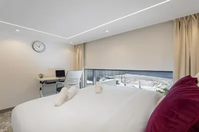 a bedroom with a large white bed and a desk at Trendy Loft Studio in Oxford Terrace JVC in Dubai