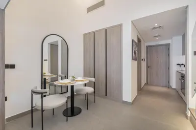 a dining room with a table and chairs and a mirror at Trendy Loft Studio in Oxford Terrace JVC in Dubai