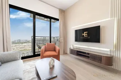 a living room with a tv and a couch and a chair at Chic Liva 1br Family-friendly Great Amenities in Nadd Shubayḩ