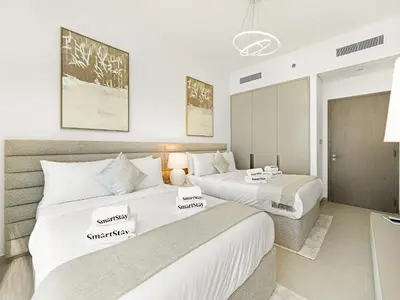 two beds in a room with white walls at SmartStay at Grande Signature - Burj Khalifa View - 5 min Dubai Mall - Downtown Dubai - Brand New Luxury Apartments in Dubai