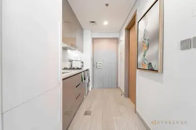 a kitchen with white cabinets and a hallway at Everluxe Modern Pool View Studio In Al Jaddaf in Dubai