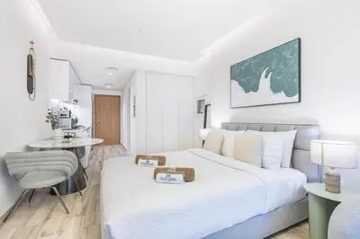 a white bedroom with a large bed and a chair at Exquisite Modern Home Minutes from Downtown Dubai in Dubai