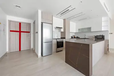 a large kitchen with a counter and a red door at 2-Bedroom Apartment in ME DO RE in Dubai