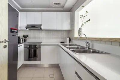 a kitchen with white cabinets and a sink at Classic Retreat in JBR with Private Beach Access in Dubai