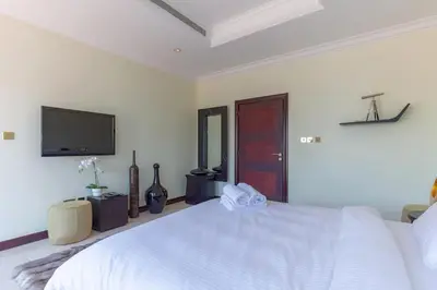 a bedroom with a white bed and a flat screen tv at Private Pool & Direct Beach Access-4BDR Villa in Dubai