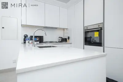 a kitchen with white cabinets and a white counter top at Mira Holiday Homes - Luxury and cosy 1 bedroom in JVC in Dubai