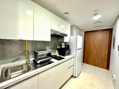 a kitchen with a sink and a refrigerator at Prime Location , Bright Studio , High Floor in Dubai