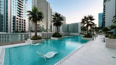 a swimming pool with a chair and palm trees on a building at Luxurious New Studio! 2 Double Beds! Sleek Design & High-End Amenities in Dubai Downtown in Dubai