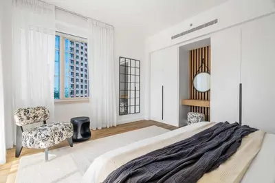 a bedroom with a bed and a chair and windows at Silkhaus Chic 3BDR & maid room in Dubai Marina in Dubai