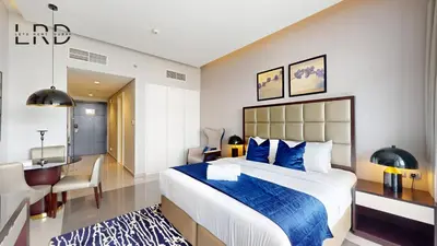 a hotel room with a large bed and a desk at Modern Studio in Majestine in Dubai